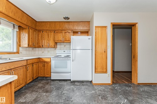 Wood cabinetry with white countertops, white tile backsplash, and dark patterned flooring - 11139 62 Avenue Nw, Edmonton, AB - Indoor Photo Showing Kitchen