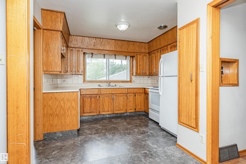 Kitchen featuring wood-finish cabinetry, white tile backsplash, a window above the sink, and white appliances - 11139 62 Avenue Nw, Edmonton, AB - Indoor Photo Showing Kitchen