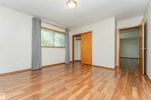 Wood-finish flooring, wood trim, flush mount ceiling light, and a window with a wood frame - 11139 62 Avenue Nw, Edmonton, AB - Indoor Photo Showing Other Room