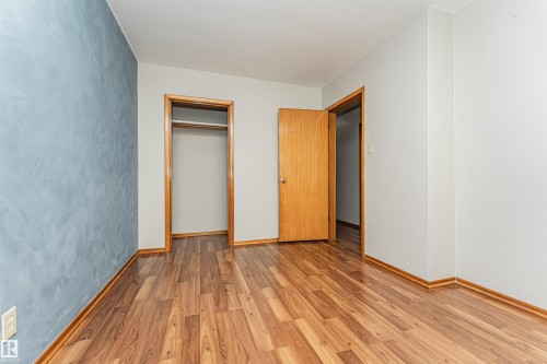 Wood-finish flooring, light blue accent wall, neutral painted walls, wood trim, and a built-in closet - 11139 62 Avenue Nw, Edmonton, AB - Indoor Photo Showing Other Room
