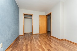 Wood-finish flooring, light blue accent wall, neutral painted walls, wood trim, and a built-in closet - 