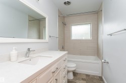 White vanity with a rectangular undermount sink, a chrome faucet, and a light-toned countertop - 