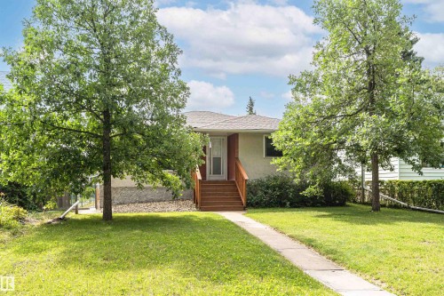 Manicured lawn, mature trees, concrete pathway, and wood-finish stairs leading to the entry - 11139 62 Avenue Nw, Edmonton, AB - Outdoor