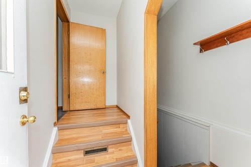 Wood-finish flooring with a wood-framed doorway, brass door hardware, and a wood wall shelf with metal hooks - 11139 62 Avenue Nw, Edmonton, AB - Indoor Photo Showing Other Room