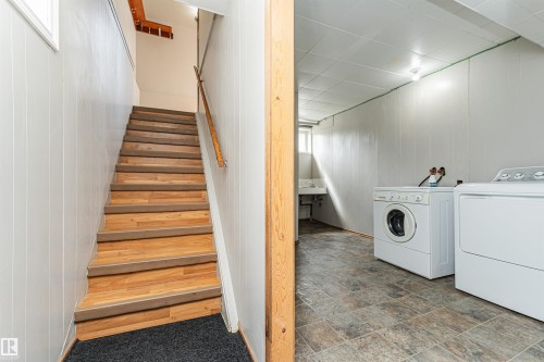 Wood-finish staircase with white paneled walls and a wood handrail - 11139 62 Avenue Nw, Edmonton, AB - Indoor Photo Showing Laundry Room