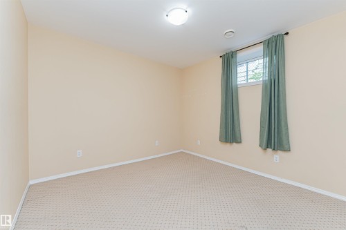Neutral wall paint with carpeted flooring, featuring a window with security bars - 11139 62 Avenue Nw, Edmonton, AB - Indoor Photo Showing Other Room