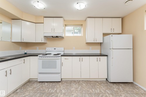 L-shaped kitchen with white cabinetry, dark countertops, and a white tile backsplash - 11139 62 Avenue Nw, Edmonton, AB - Indoor Photo Showing Kitchen