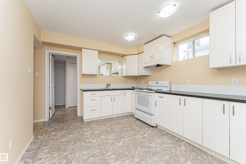 Kitchen featuring white cabinetry, dark countertops, white tile backsplash, and a white electric range - 11139 62 Avenue Nw, Edmonton, AB - Indoor Photo Showing Kitchen