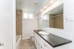 Vanity with integrated sink, white cabinetry, and dark speckled countertop - 