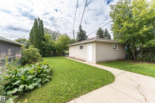 Detached garage with stucco exterior, concrete pathway, and surrounding green lawn - 11139 62 Avenue Nw, Edmonton, AB - Outdoor