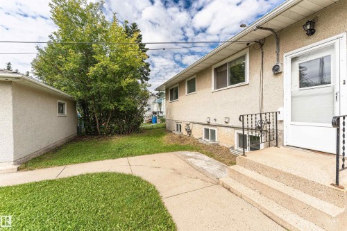 Stucco exterior with multiple windows, concrete steps, and black metal handrails - 11139 62 Avenue Nw, Edmonton, AB - Outdoor With Exterior