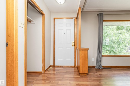 Wood-finish flooring, white paneled entry door, built-in wooden half-wall, wood trim, and a large window - 11139 62 Avenue Nw, Edmonton, AB - Indoor Photo Showing Other Room