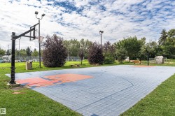 Outdoor sports court with blue and orange surfacing, surrounded by green landscaping - 