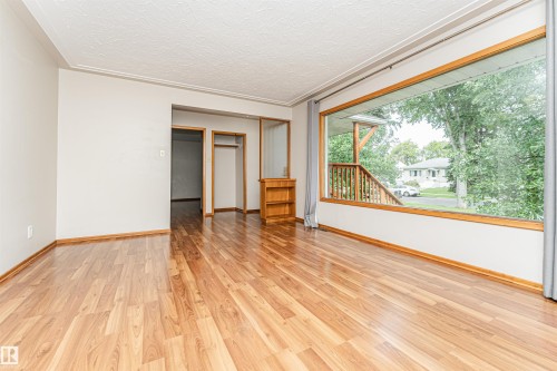 Wood-finish flooring with a large picture window, textured ceiling, and built-in shelving - 11139 62 Avenue Nw, Edmonton, AB - Indoor Photo Showing Other Room