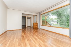 Wood-finish flooring with a large picture window, textured ceiling, and built-in shelving - 