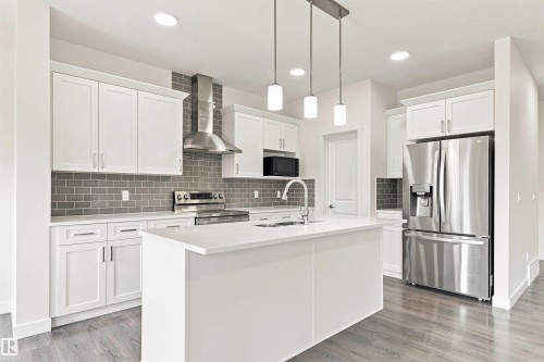 Modern kitchen featuring white cabinetry, a large kitchen island with an undermount sink, stainless steel appliances, a tile backsplash, and recessed lighting - 22019 82 Avenue Nw, Edmonton, AB - Indoor Photo Showing Kitchen With Stainless Steel Kitchen With Upgraded Kitchen