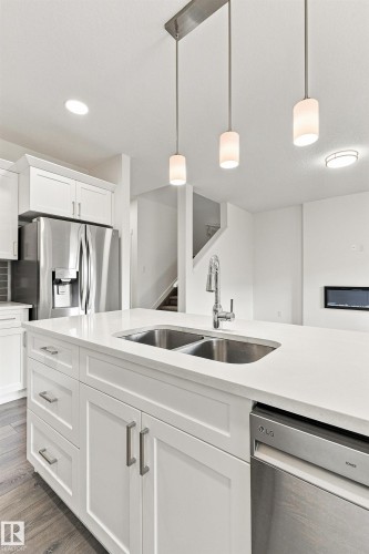 Kitchen island featuring a double basin sink, stainless steel dishwasher, and white cabinetry with brushed nickel hardware - 22019 82 Avenue Nw, Edmonton, AB - Indoor Photo Showing Kitchen With Double Sink With Upgraded Kitchen