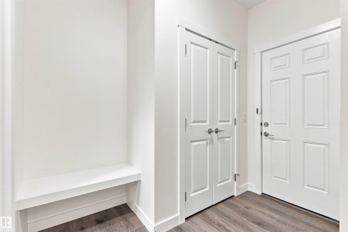 Built-in bench seating, wood-finish flooring, and white paneled doors - 22019 82 Avenue Nw, Edmonton, AB - Indoor Photo Showing Other Room