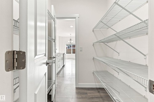 Pantry with wood-finish flooring, white wire shelving, and a white paneled door - 22019 82 Avenue Nw, Edmonton, AB - Indoor