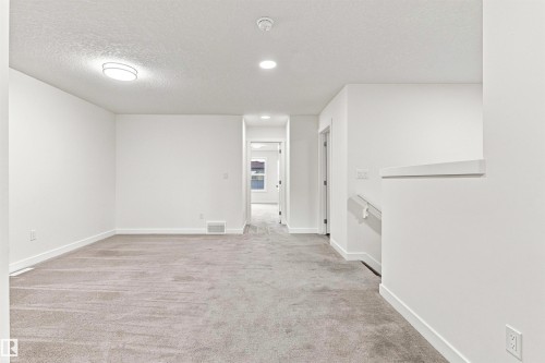 Light gray carpeting, recessed lighting, flush-mount ceiling fixture, white walls, and a staircase with a partial wall - 22019 82 Avenue Nw, Edmonton, AB - Indoor Photo Showing Other Room