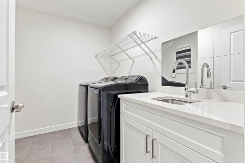 Laundry area featuring tile flooring, white cabinetry, a countertop with an undermount sink, and a chrome faucet - 22019 82 Avenue Nw, Edmonton, AB - Indoor Photo Showing Laundry Room