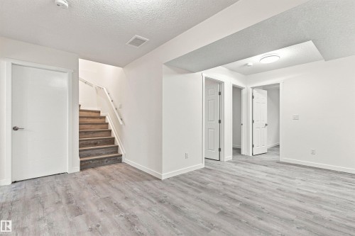 Light wood-finish flooring, white walls, wood staircase with white railing, recessed lighting, and white panel doors - 22019 82 Avenue Nw, Edmonton, AB - Indoor Photo Showing Other Room