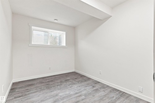 Recessed window with white louvered blinds, white painted walls, and wood-finish flooring - 22019 82 Avenue Nw, Edmonton, AB - Indoor Photo Showing Other Room