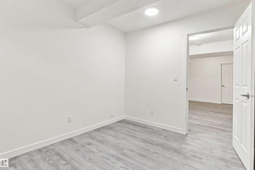 Room featuring wood-finish flooring, recessed lighting, and a white paneled door - 22019 82 Avenue Nw, Edmonton, AB - Indoor Photo Showing Other Room