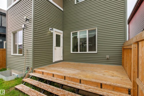 Rear exterior with green horizontal siding, white trim windows, and a wood deck featuring multiple steps - 22019 82 Avenue Nw, Edmonton, AB - Outdoor
