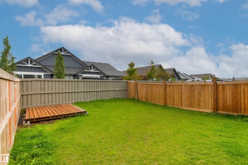 Expansive green lawn with a wood-finish fence and a small wooden deck - 22019 82 Avenue Nw, Edmonton, AB - Outdoor