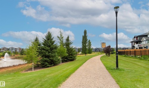 Manicured green space featuring a paved pathway, mature trees, and a visible water feature with a fountain - 22019 82 Avenue Nw, Edmonton, AB - Outdoor With View