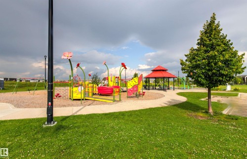 Recreational outdoor space featuring a playground, swings, and a red-roofed gazebo, with a paved pathway and mature trees - 22019 82 Avenue Nw, Edmonton, AB - Outdoor