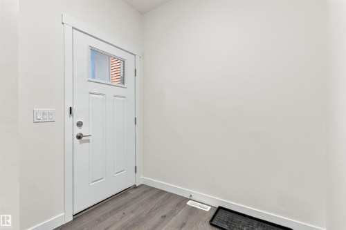 Entry with a paneled door featuring an upper window, satin nickel hardware, and wood-finish flooring - 22019 82 Avenue Nw, Edmonton, AB - Indoor Photo Showing Other Room
