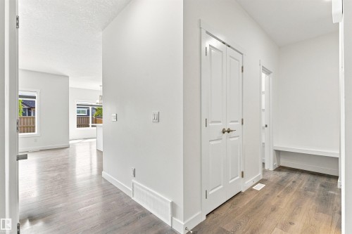Bright interior with wood-finish flooring, white walls, built-in closet with bi-fold doors, and a built-in bench - 22019 82 Avenue Nw, Edmonton, AB - Indoor Photo Showing Other Room