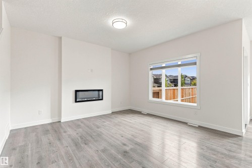 Integrated electric fireplace, wood-finish flooring, white trim, recessed lighting, and large window - 22019 82 Avenue Nw, Edmonton, AB - Indoor With Fireplace
