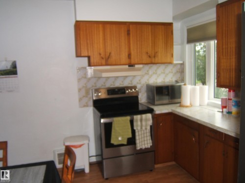 Warm wood cabinetry with stainless steel appliances, ceramic tile backsplash, and white countertops - 4809 47A Street, Two Hills, AB - Indoor Photo Showing Kitchen