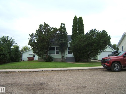 Charming single-story home with classic architectural details, framed by mature evergreen landscaping - 4809 47A Street, Two Hills, AB - Outdoor