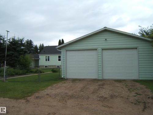 Spacious two-car garage with dual overhead doors and light-colored siding - 4809 47A Street, Two Hills, AB - Outdoor