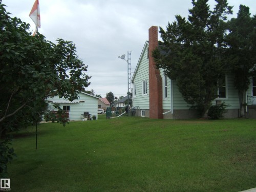 Spacious grounds featuring a manicured lawn surrounded by mature landscaping and established trees - 4809 47A Street, Two Hills, AB - Outdoor