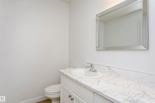 Vanity with an integrated white sink and chrome faucet, set against a patterned countertop with a matching backsplash - 37 Suntree Promenade, Leduc, AB - Indoor Photo Showing Bathroom