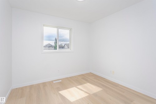 Recessed ceiling light, neutral wall paint, wood-finish flooring, white trim, and a window with a white frame - 37 Suntree Promenade, Leduc, AB - Indoor Photo Showing Other Room