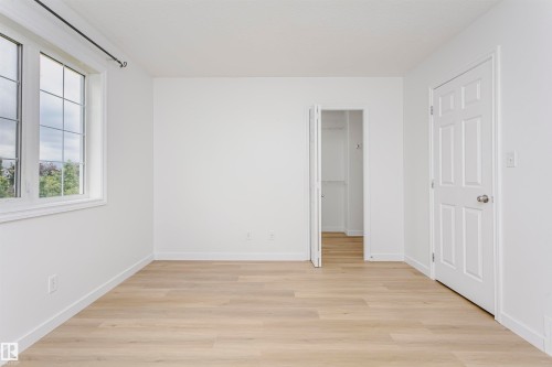 Light wood-finish flooring complemented by white walls, a multi-pane window, and a paneled door - 37 Suntree Promenade, Leduc, AB - Indoor Photo Showing Other Room