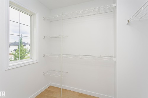 White wire shelving system, large multi-pane window, light wood-finish flooring, and white walls - 37 Suntree Promenade, Leduc, AB - Indoor With Storage