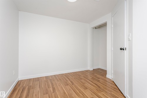 Hardwood-finish flooring, white walls, flush-mount ceiling light, white trim, and a closet with a hanging rod - 37 Suntree Promenade, Leduc, AB - Indoor Photo Showing Other Room