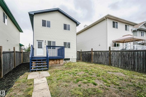 Rear exterior featuring beige horizontal siding, a blue-painted deck with steps, a wood privacy fence, and a grass lawn - 37 Suntree Promenade, Leduc, AB - Outdoor With Deck Patio Veranda With Exterior