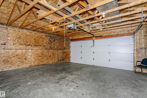 Concrete flooring, wood-paneled walls, exposed wood beam ceiling, white overhead garage door, built-in overhead lighting - 37 Suntree Promenade, Leduc, AB - Indoor Photo Showing Garage