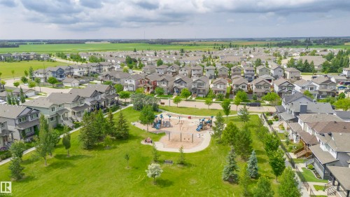 Expansive green space with mature trees, children's playground equipment, and surrounding residential properties - 37 Suntree Promenade, Leduc, AB - Outdoor With View