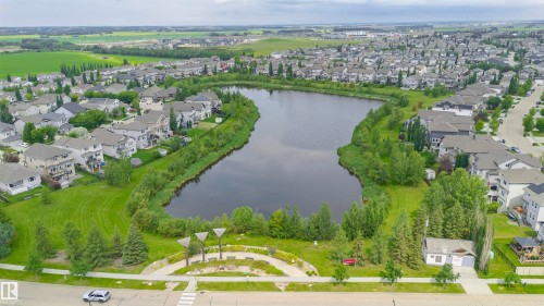 Aerial perspective showcasing a residential area with a prominent central lake, surrounding greenery, and extensive housing - 37 Suntree Promenade, Leduc, AB - Outdoor With View