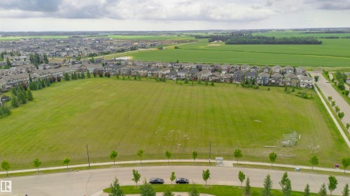 Expansive green space bordered by residential homes, a paved pathway, and mature trees - 37 Suntree Promenade, Leduc, AB - Outdoor With View