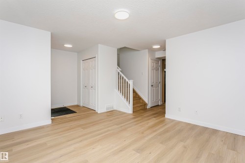 Light wood-finish flooring, white walls, and a staircase with white railings - 37 Suntree Promenade, Leduc, AB - Indoor Photo Showing Other Room
